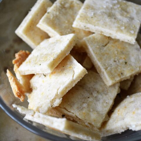 Preheat oven to 400 degrees. In a small bowl, whisk together ½ teaspoon of honey and 1 tablespoon of coconut oil until you have a creamy consistency. Set this spread aside for now. In a large bowl, combine 1 cup of gluten free flour, ½ teaspoon of sea salt and 1 teaspoon of ranch flavored powder. Slowly pour in ⅓ cup of water to the flour mixture. (I add a little at a time, while mixing the dough with my hands.) Once you have added all the water, add in the honey/oil spread, and continue mixing. When you are finished, form the dough into a ball and place it between two sheets of parchment paper. Begin to roll it out, trying to get the dough as thin as possible without tearing. Once you are finished rolling, remove the top parchment paper sheet, keeping the dough on the bottom sheet and place it onto a baking sheet. Drizzle the top of the dough with 1-2 teaspoon of olive oil and a dash of additional sea salt and ranch powder. Bake for about 20 minutes.