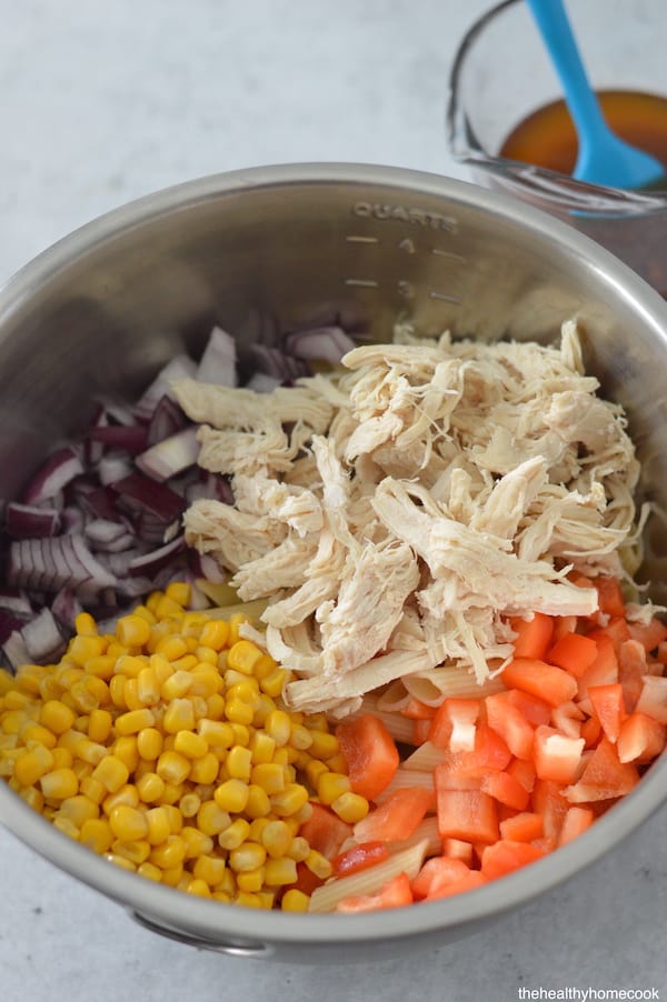 Chicken, bell pepper, corn and red onion tossed together in large bowl with pasta.