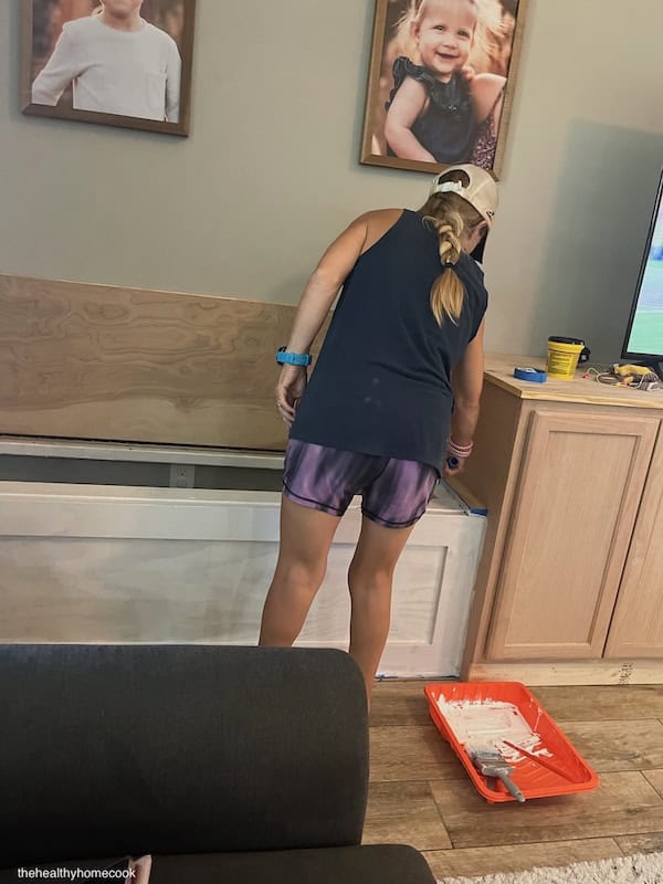 Image of woman painting storage bench white.