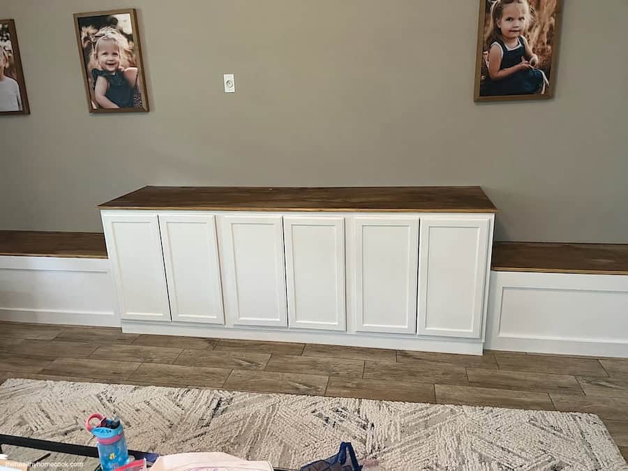 Image of cabinets and storage bench painted white and wooden top stained brown.